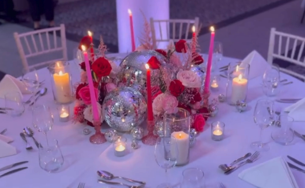 A beautifully arranged table with pink roses, candles, and decorative elements.