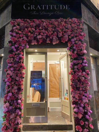 A shop front adorned with pink flowers, featuring the name 'Gratitude' above the door.