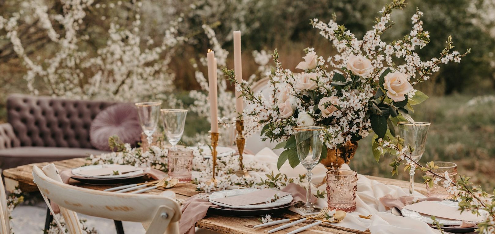 A beautifully set outdoor dining table with floral arrangements and elegant decor.