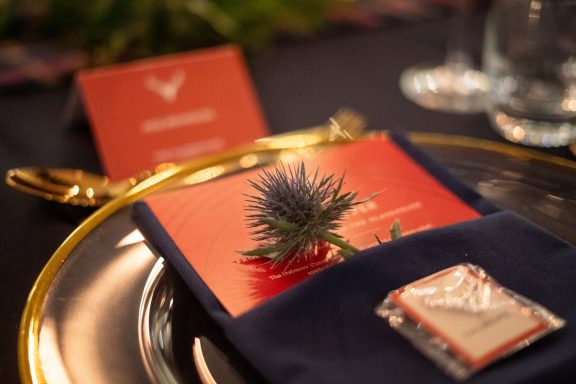 Elegant table setting featuring a menu card, a floral decoration, and a favour on a gold plate.