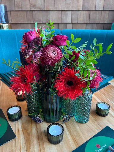 Vibrant bouquet of red and pink flowers in decorative vases on a wooden table.