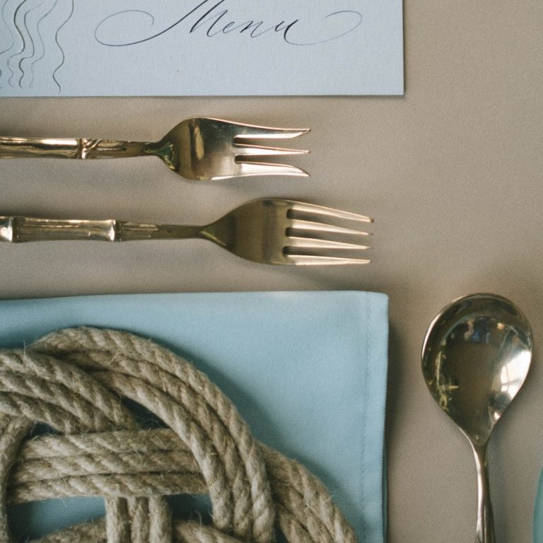 Elegant table setting featuring a menu card, forks, spoon, and decorative rope.