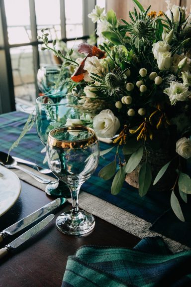 Table setting with glassware, cutlery, and a decorative floral arrangement.